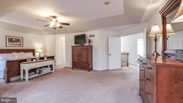 bedroom with light carpet, ceiling fan, and a tray ceiling