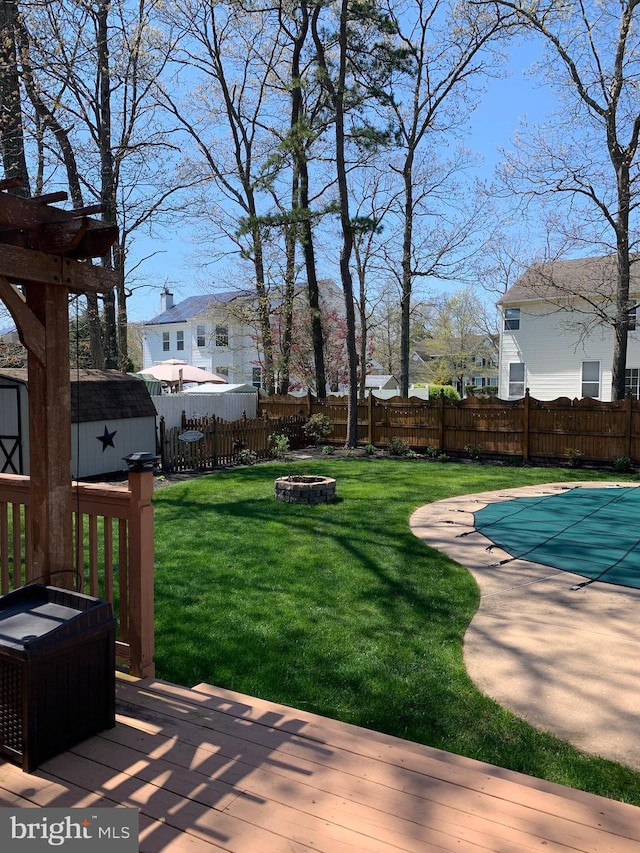 view of yard with a pergola, a swimming pool side deck, a shed, and an outdoor fire pit