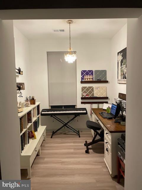 home office with a chandelier and light hardwood / wood-style floors