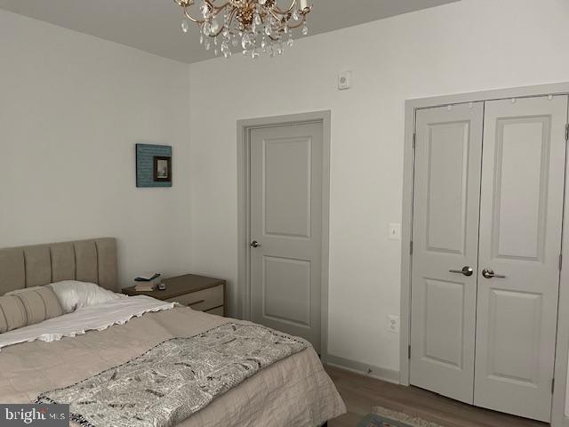 bedroom with dark hardwood / wood-style floors, a closet, and a notable chandelier