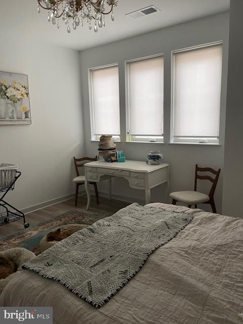 bedroom with dark wood-type flooring and a notable chandelier