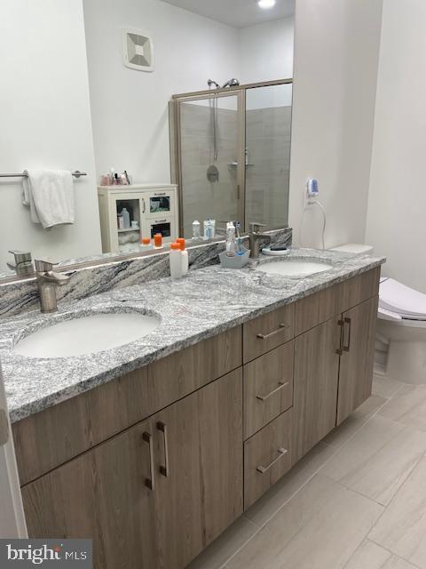 bathroom featuring a shower with shower door, vanity, and toilet