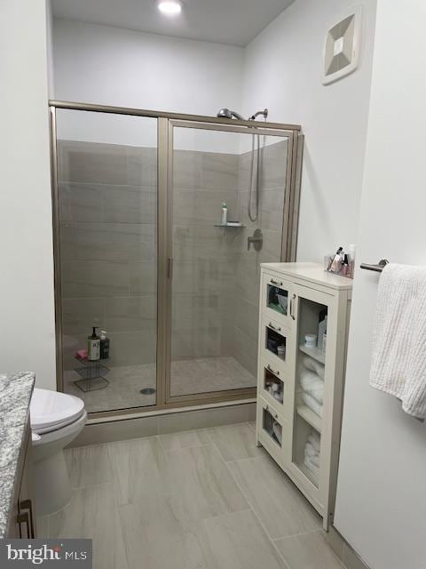 bathroom featuring a shower with shower door, vanity, and toilet