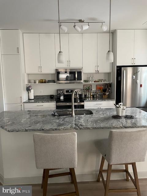 kitchen with stainless steel appliances, dark stone countertops, and decorative light fixtures