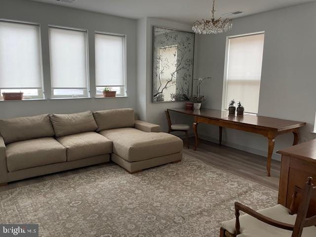 living room with light hardwood / wood-style floors and a notable chandelier