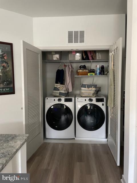 clothes washing area with separate washer and dryer and dark hardwood / wood-style floors