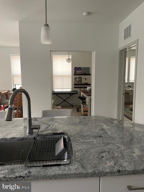 kitchen with sink, hanging light fixtures, and stone counters