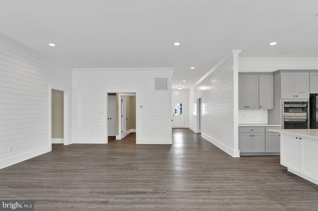 unfurnished living room featuring dark wood-type flooring and ornamental molding