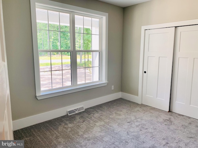 unfurnished bedroom featuring light colored carpet and a closet