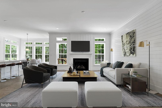 living room with wood walls, crown molding, and hardwood / wood-style flooring