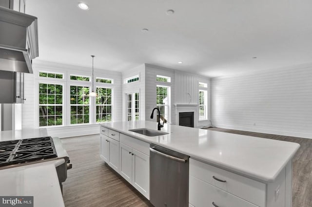 kitchen with a center island with sink, dishwasher, hanging light fixtures, white cabinets, and sink