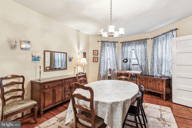 dining area with dark wood-type flooring and a chandelier