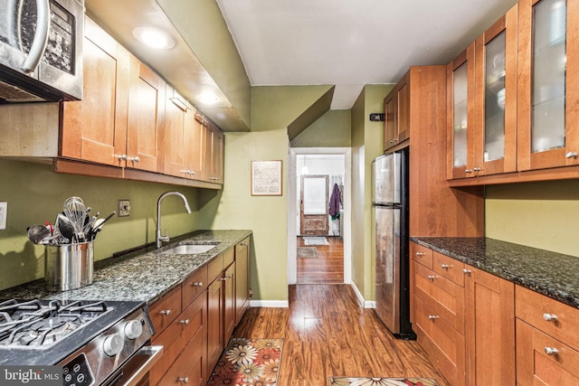 kitchen featuring sink, appliances with stainless steel finishes, dark hardwood / wood-style floors, and dark stone counters