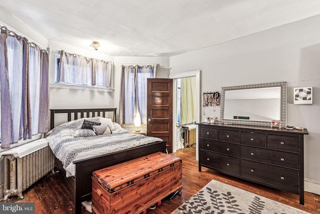 bedroom with dark hardwood / wood-style floors and radiator