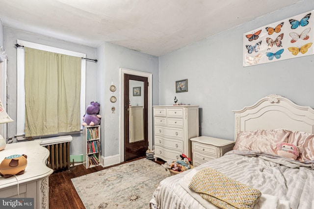 bedroom with dark hardwood / wood-style floors and radiator