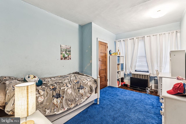 bedroom with dark colored carpet and radiator heating unit