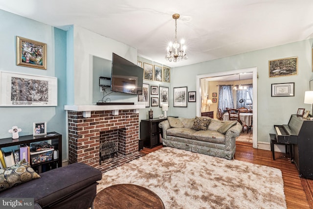 living room with a fireplace, hardwood / wood-style floors, and an inviting chandelier