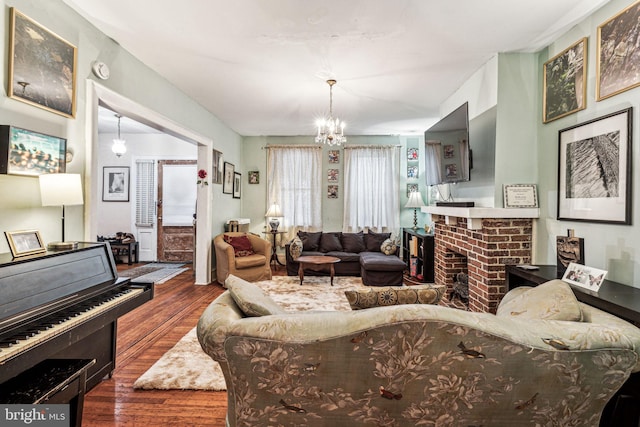 living room with a chandelier, a brick fireplace, and dark hardwood / wood-style flooring