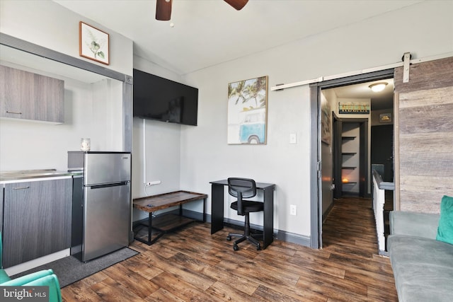 home office with ceiling fan, a barn door, and dark wood-type flooring