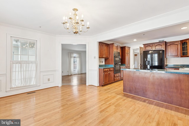 kitchen featuring light hardwood / wood-style flooring, hanging light fixtures, a notable chandelier, ornamental molding, and black appliances