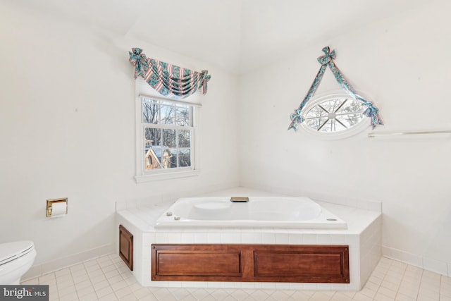 bathroom with toilet, tile patterned floors, and a relaxing tiled tub