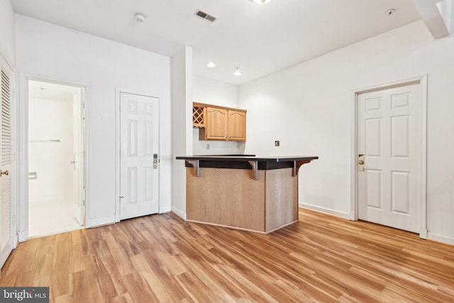 kitchen with a breakfast bar, light hardwood / wood-style flooring, and kitchen peninsula