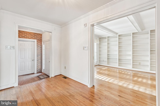 unfurnished room featuring built in shelves, hardwood / wood-style flooring, and crown molding