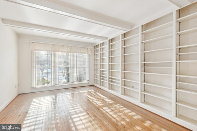 spare room featuring built in shelves, beamed ceiling, and wood-type flooring