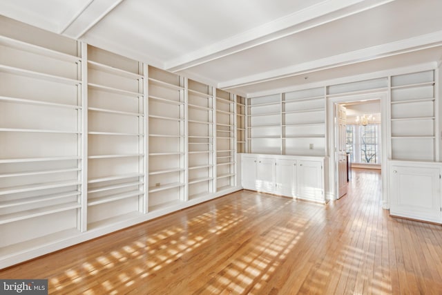 empty room with built in shelves, hardwood / wood-style floors, an inviting chandelier, and beamed ceiling