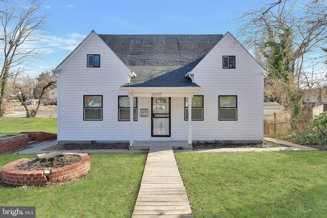 rear view of house with covered porch, a lawn, roof with shingles, and fence