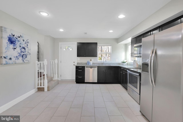 kitchen featuring dark cabinetry, recessed lighting, appliances with stainless steel finishes, baseboards, and light stone countertops