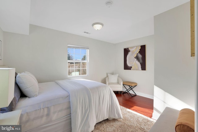 bedroom featuring visible vents, baseboards, and wood finished floors