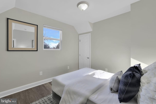 bedroom featuring dark wood-style floors, baseboards, and lofted ceiling