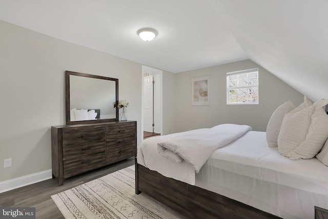 bedroom featuring baseboards, lofted ceiling, and wood finished floors