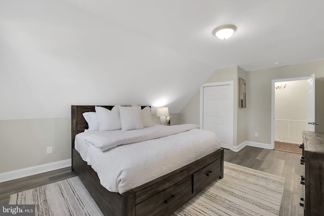 bedroom with baseboards, lofted ceiling, a closet, and wood finished floors