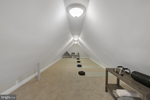 workout area featuring baseboards, lofted ceiling, and carpet