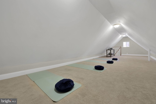 exercise room featuring vaulted ceiling, baseboards, and carpet floors