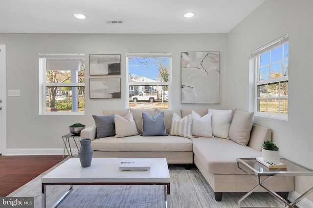 living room with recessed lighting, plenty of natural light, wood finished floors, and baseboards