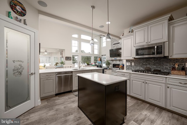 kitchen featuring a kitchen island, stainless steel appliances, tasteful backsplash, sink, and light wood-type flooring