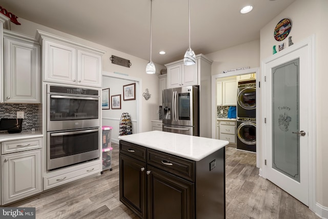 kitchen featuring stacked washer / dryer, decorative backsplash, appliances with stainless steel finishes, and white cabinetry