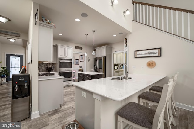 kitchen featuring kitchen peninsula, stainless steel appliances, decorative light fixtures, a kitchen breakfast bar, and sink