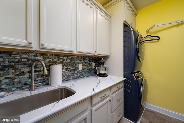 laundry room featuring stacked washer and dryer, cabinets, dark hardwood / wood-style flooring, and sink