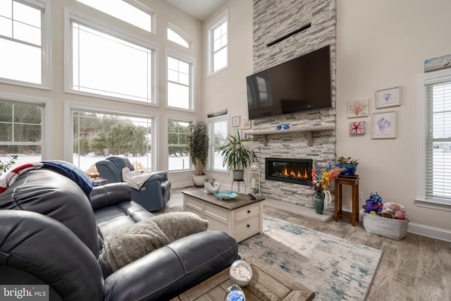 living room with light hardwood / wood-style floors, plenty of natural light, and a stone fireplace