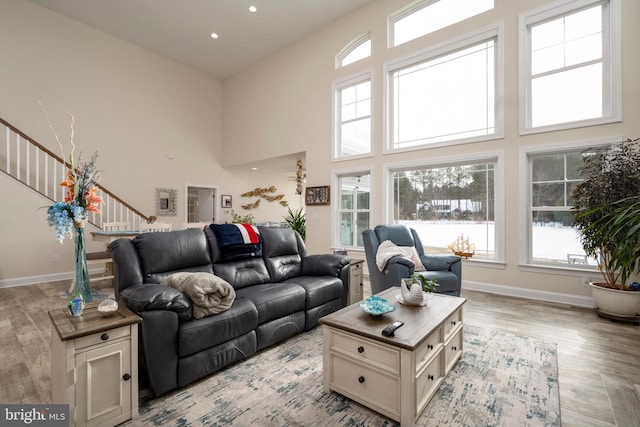 living room with light hardwood / wood-style floors and a towering ceiling