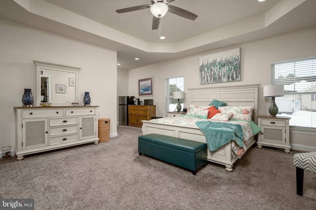 bedroom with ceiling fan, stainless steel fridge, a tray ceiling, and carpet flooring