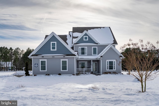 snow covered back of property featuring a porch