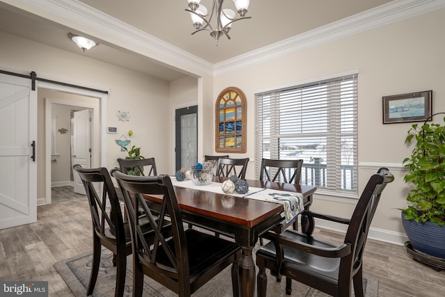 dining area with a chandelier, wood-type flooring, ornamental molding, and a barn door