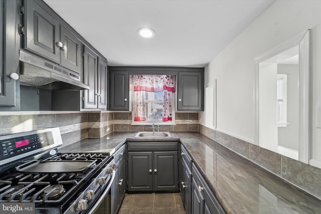 kitchen featuring dark tile patterned floors, sink, backsplash, and stainless steel range with gas cooktop