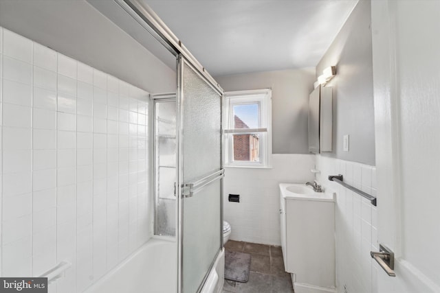 full bathroom with toilet, vanity, tile walls, tile patterned floors, and enclosed tub / shower combo