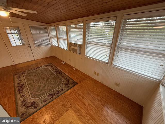 unfurnished sunroom featuring wooden ceiling, cooling unit, vaulted ceiling, and ceiling fan